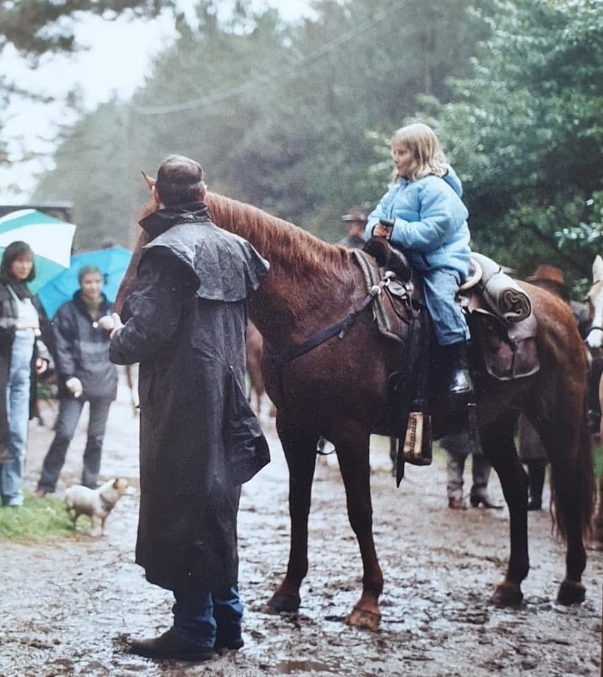 Marieke als klein meisje op een paard, haar vader ernaast in regenjas